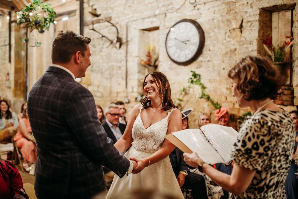 Wedding ceremony in a rustic stone-walled venue with exposed beams and vintage clock decor.