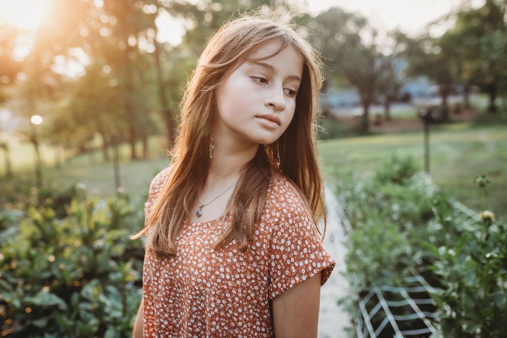 Summer garden portrait with warm sunset lighting and floral peach top.