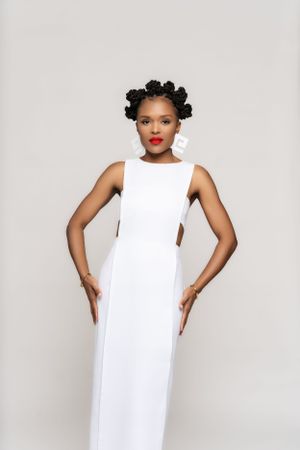 Elegant white floor-length gown with cutout details and red lipstick styling for a formal event.