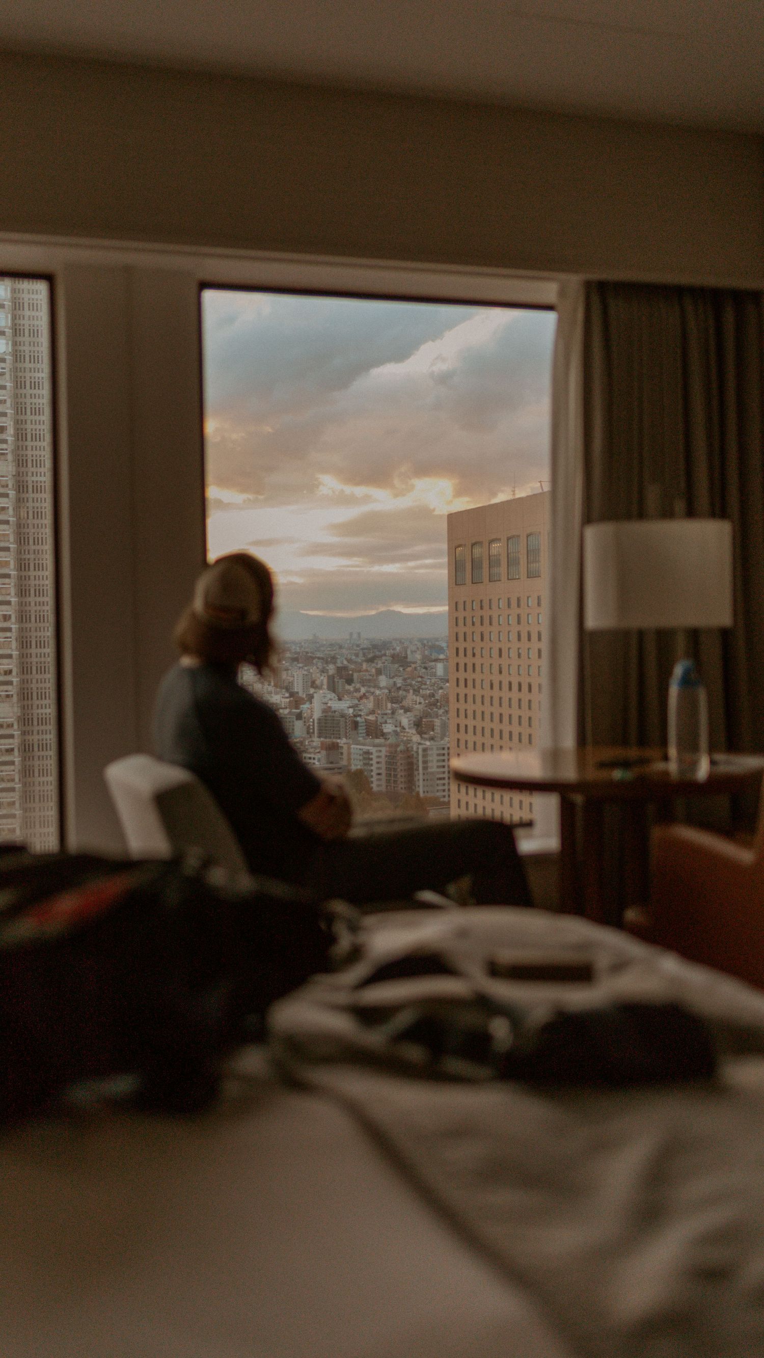 a man sitting and looking out the window of a skyscraper at the city of Tokyo below