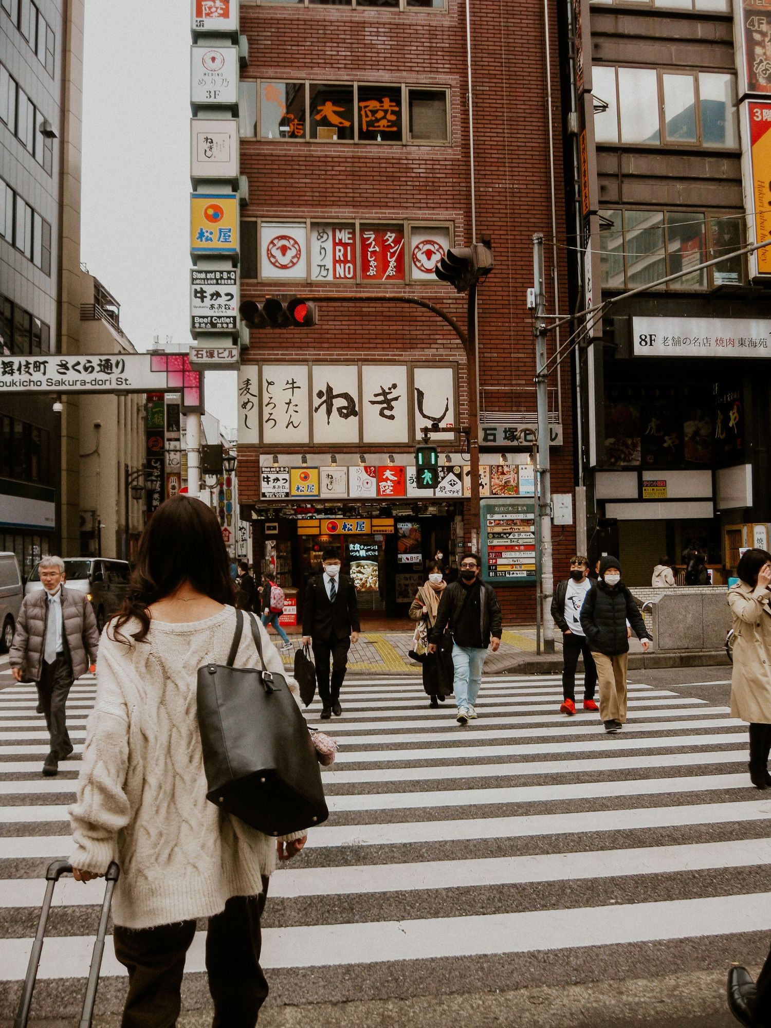 a crosswalk in Tokyo with a woman in a sweater walking across