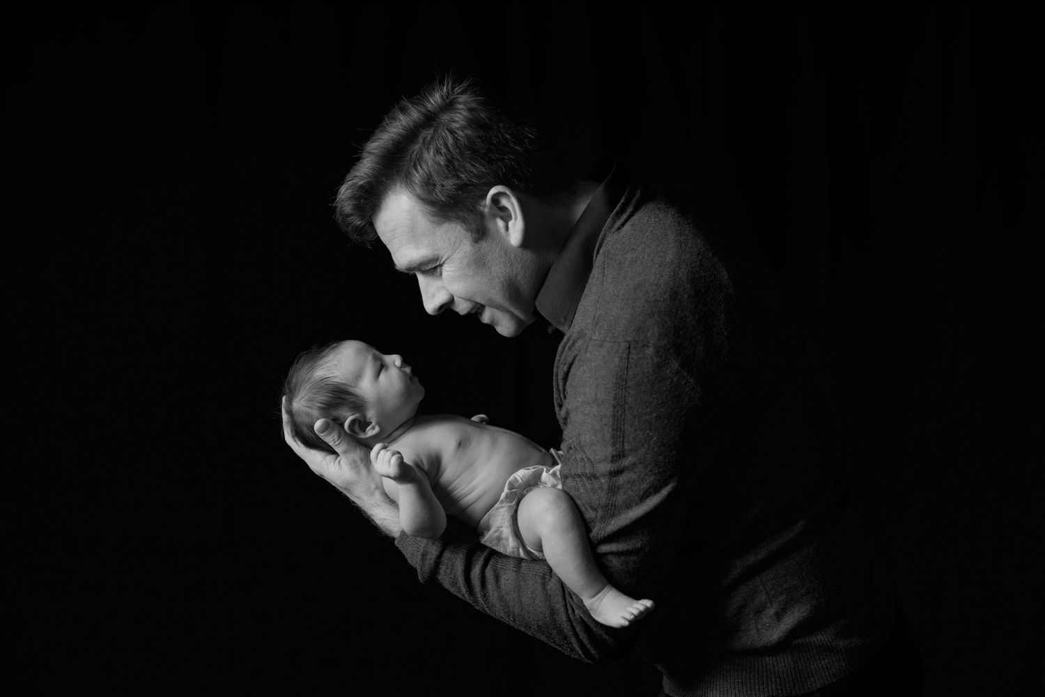 Intimate black and white portrait showing tender moment with sleeping newborn.