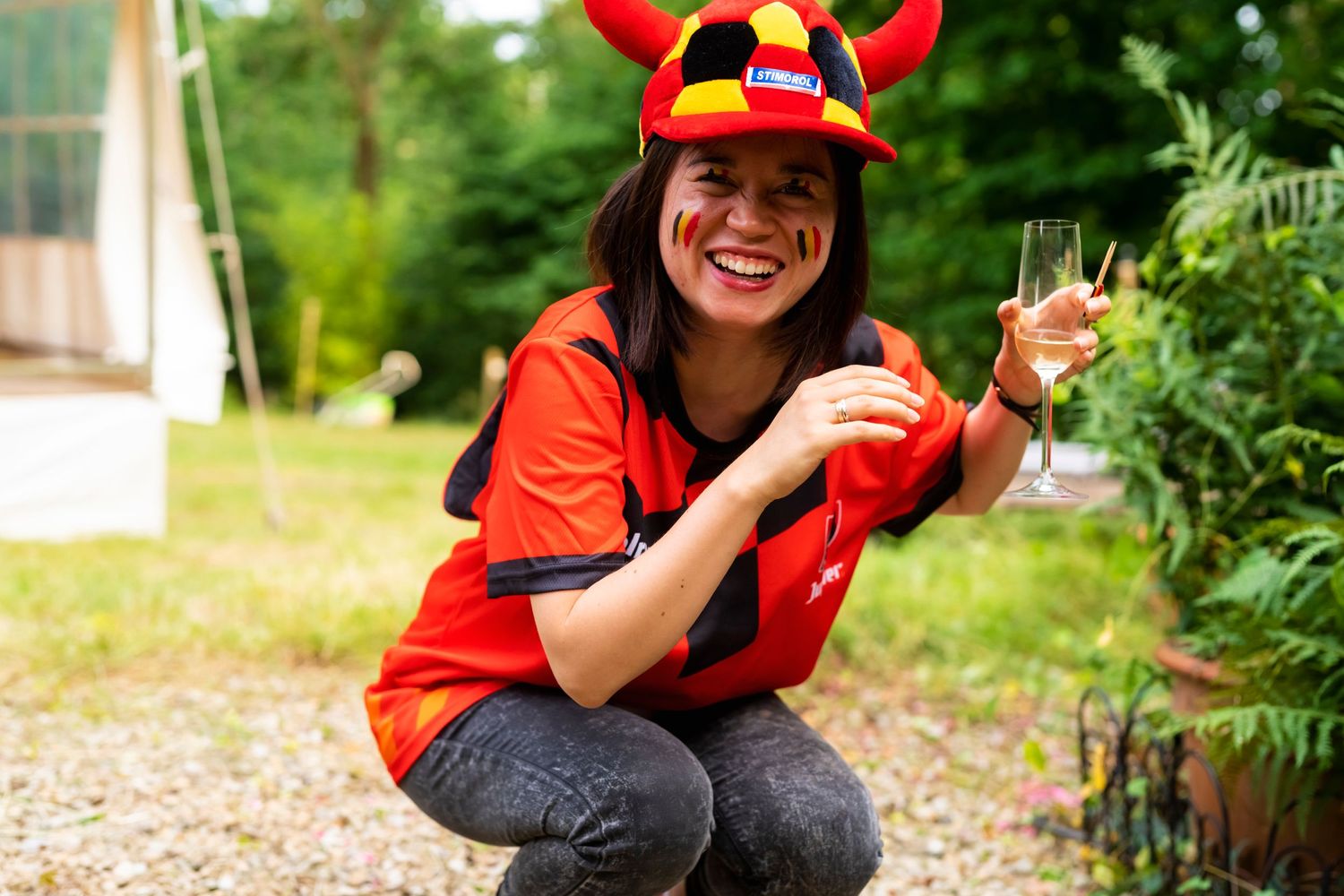Person in red costume with horned hat enjoying a drink outdoors.