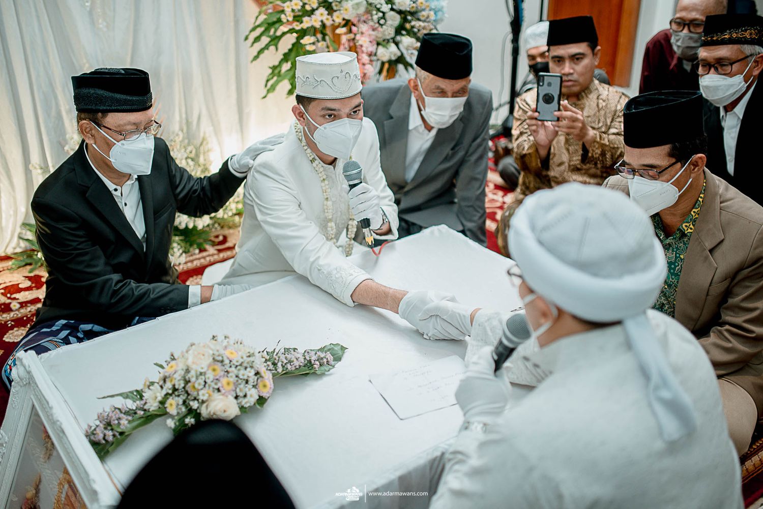 Religious officials and attendees gather around a table during a traditional ceremony.