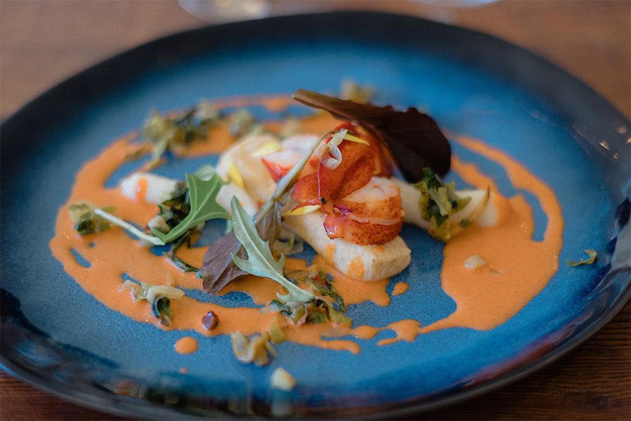 Series of plated dishes featuring seafood in a vibrant orange sauce on blue ceramic plates.