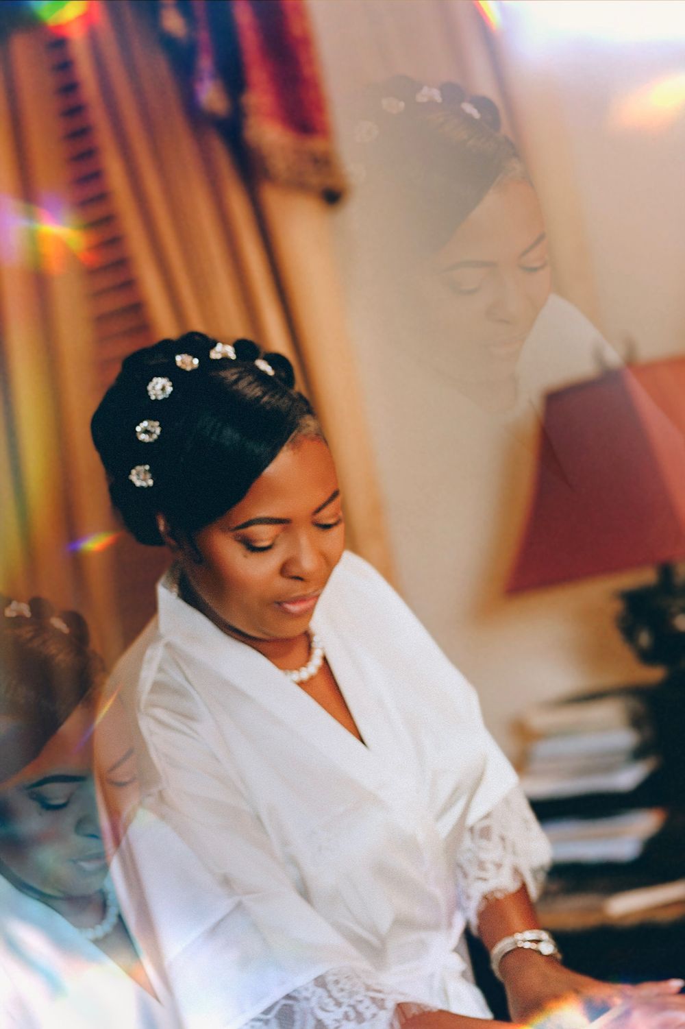 Bride getting ready in white robe with jeweled hair accessories.