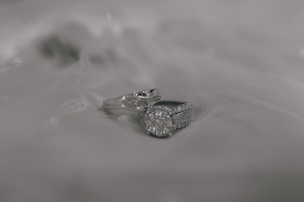 Close-up of diamond engagement ring and wedding band on textured surface.