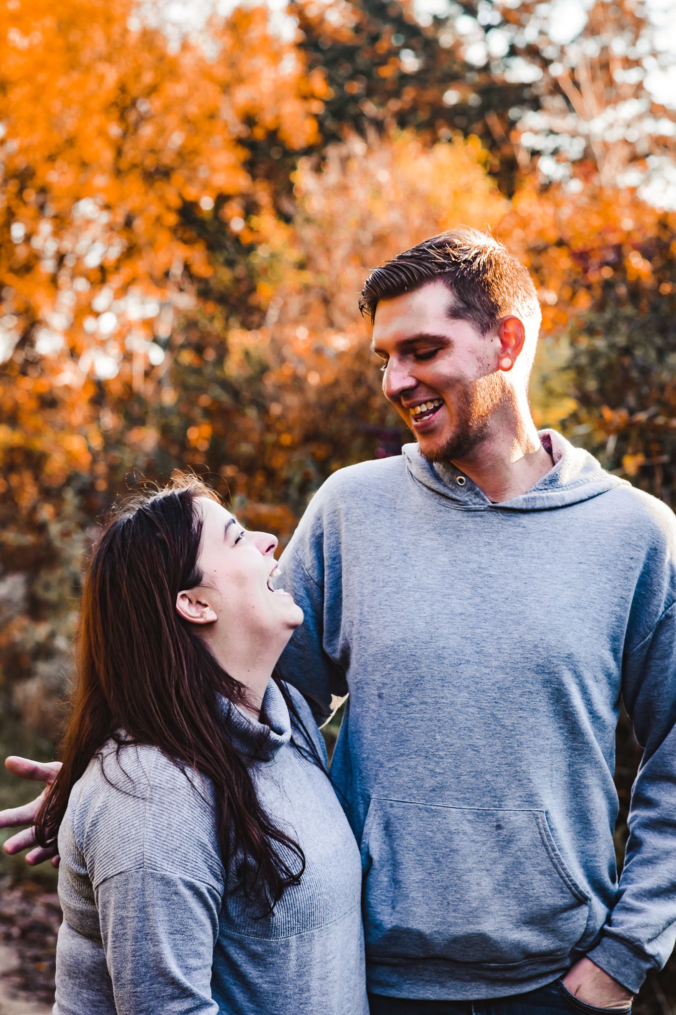 A couple sharing a joyful moment together among vibrant autumn foliage.