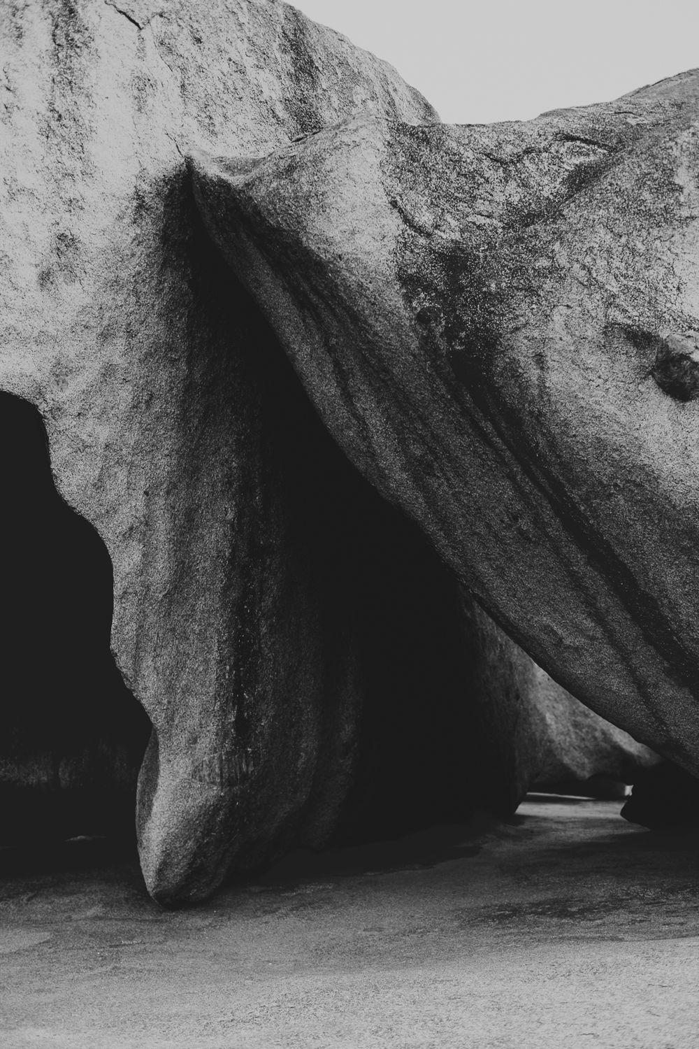 Dramatic black and white photograph of a natural rock formation with cave-like openings and angular shadows.