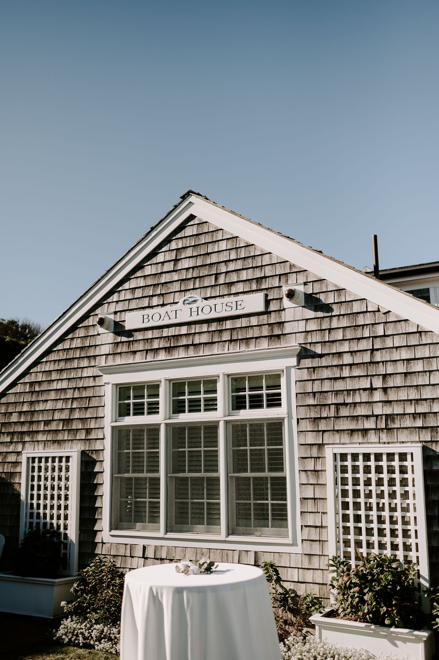 Coastal beach house exterior with weathered shingle siding and white trim windows.