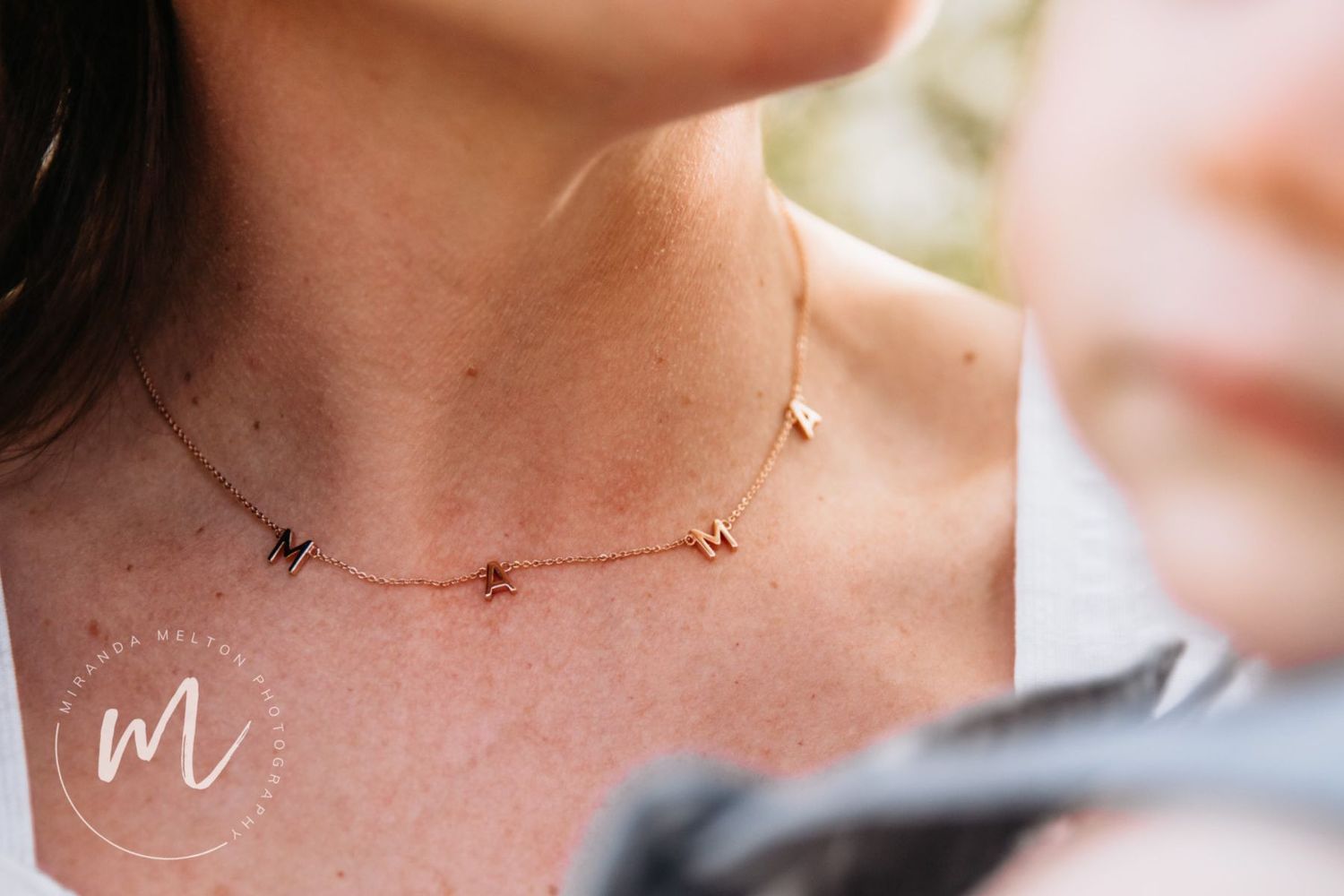 A close-up professional photo of a necklace that reads "Mama" is displayed as a concept for family photo ideas in the Twin Cities.