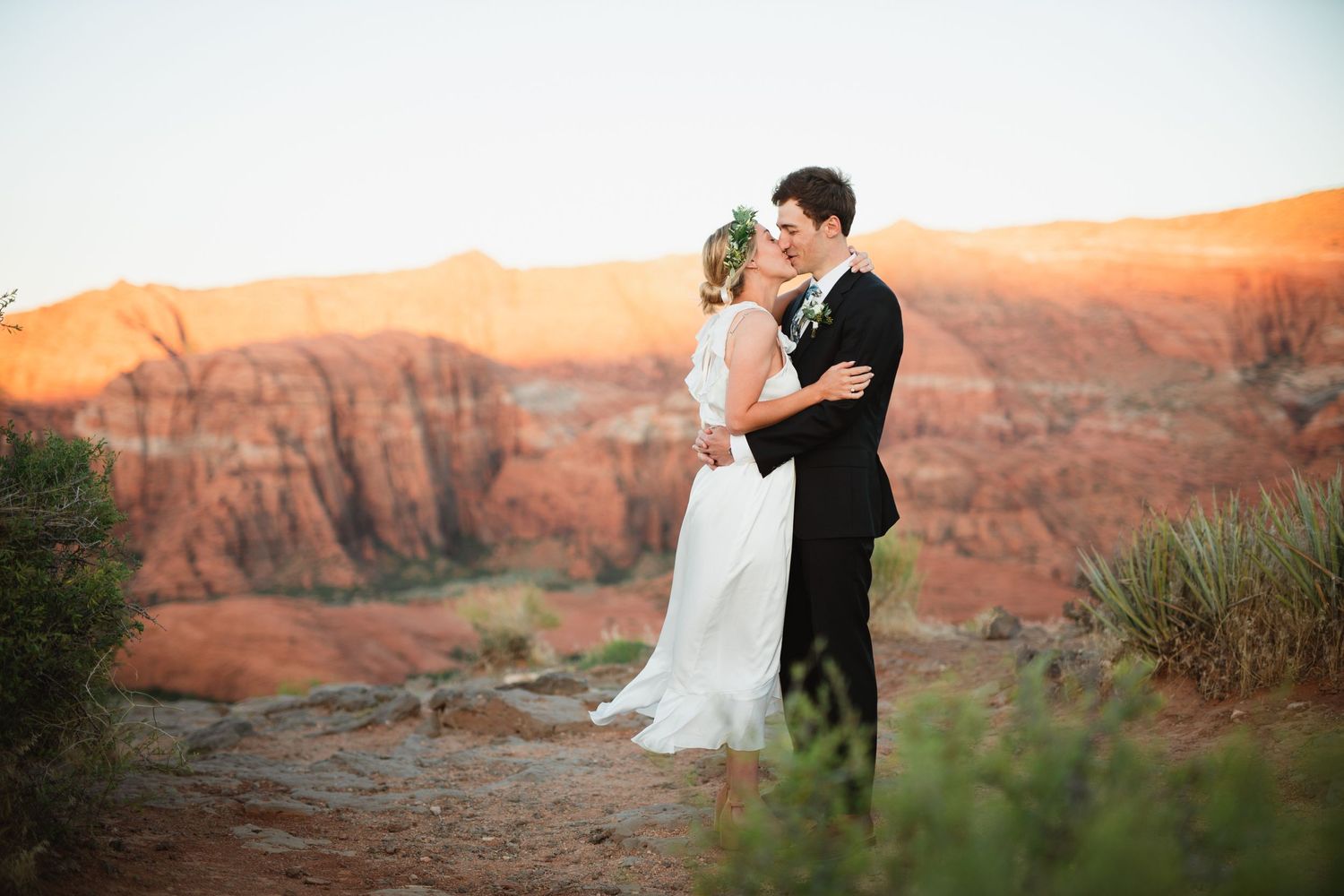 Bride and groom sharing a tender moment at golden hour with glowing red sandstone canyon formations behind them.