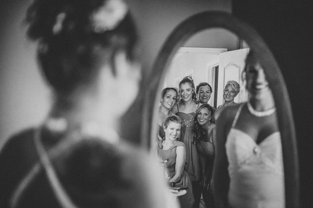 the whole bridal party is looking at the bride in the mirror