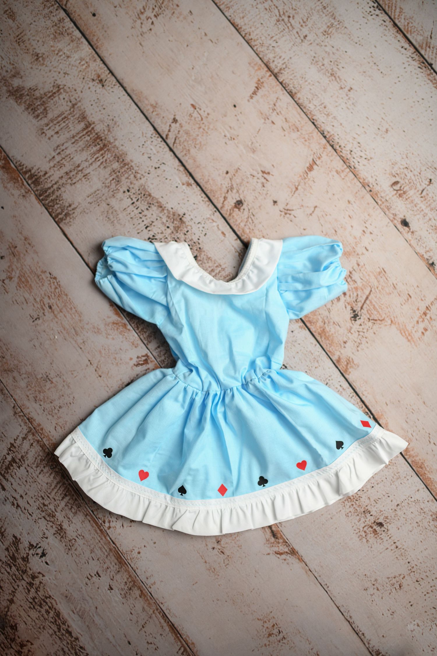 Baby blue dress with white trim and heart details on wooden floor.