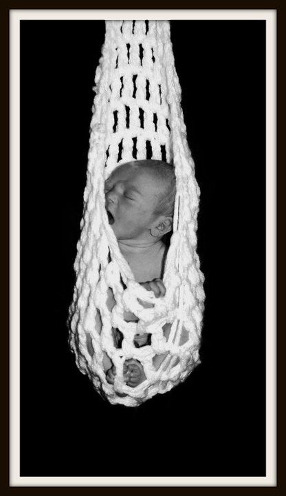 Black and white portrait of sleeping newborn in suspended macrame holder.