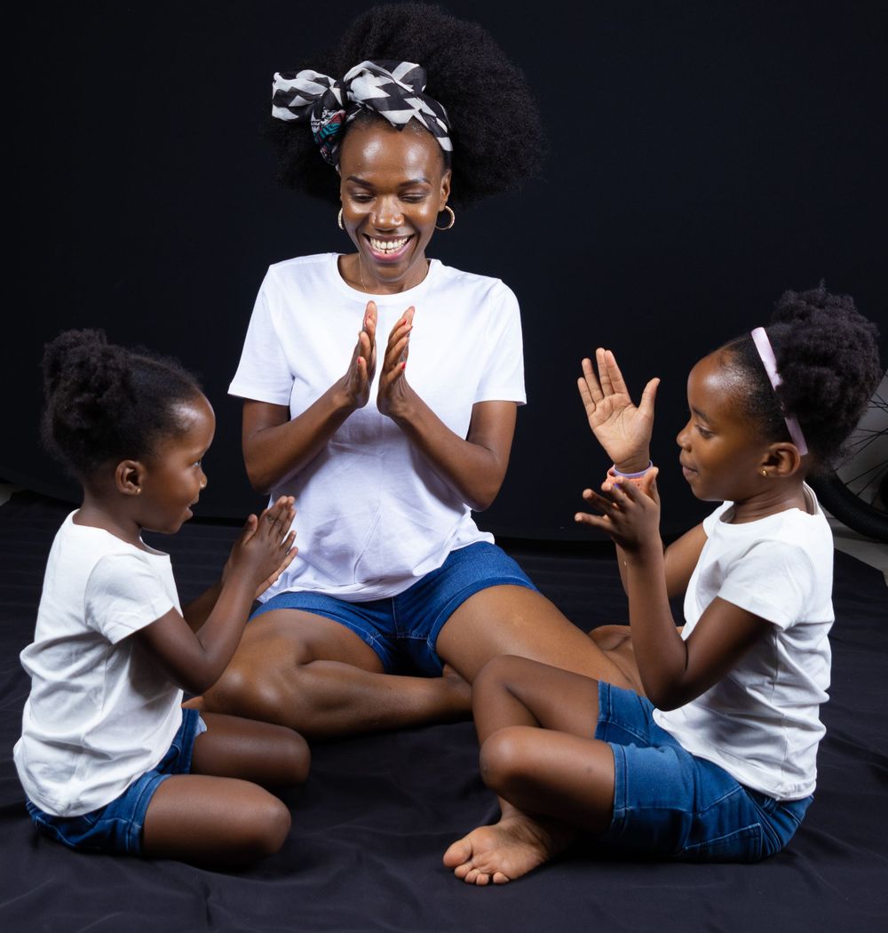 Three people in matching white shirts and blue shorts playing a clapping game together.