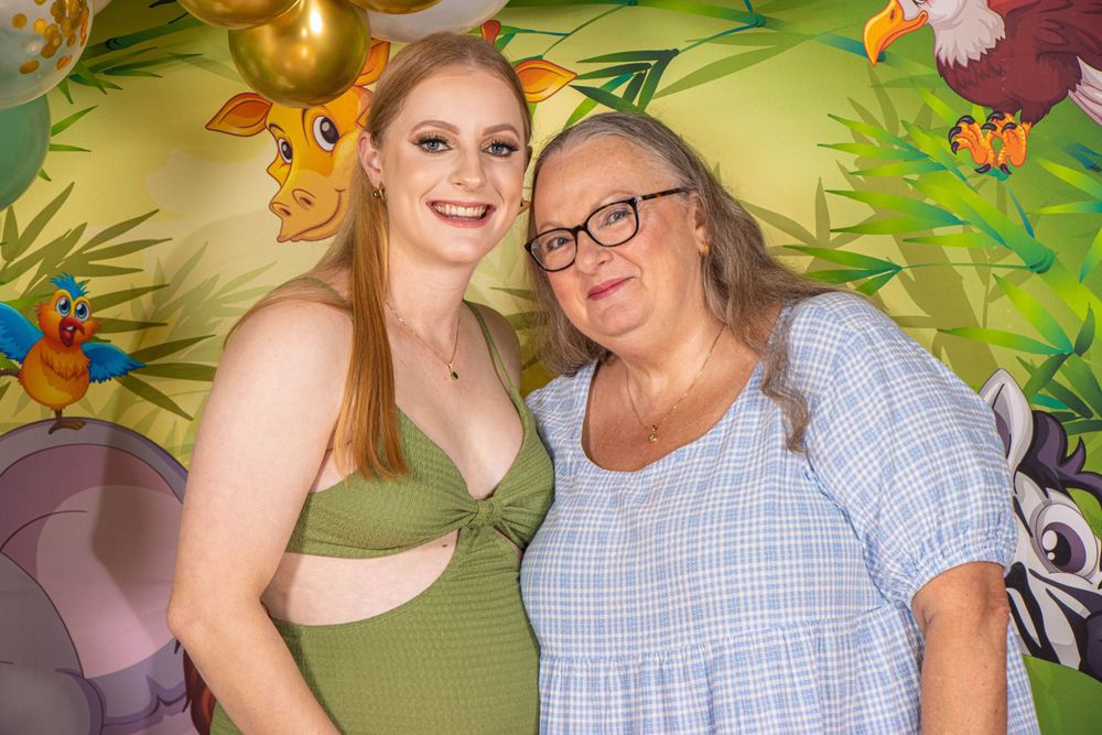 Celebratory moment at a baby shower with safari-themed decorations and balloon arch in the background.