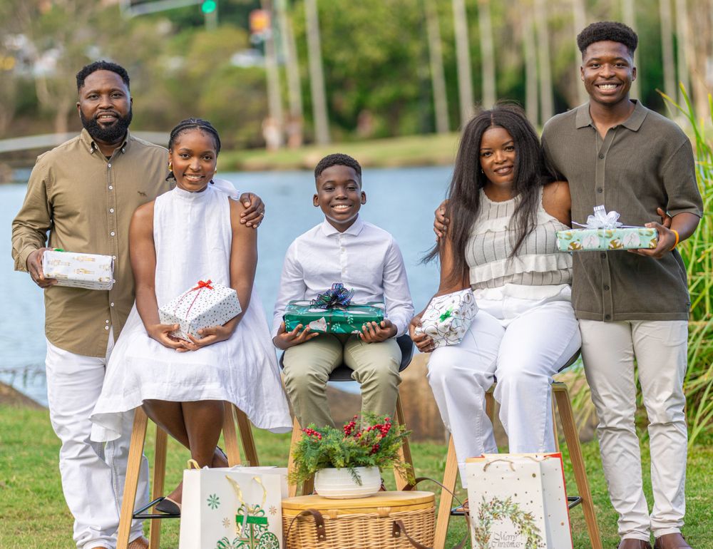 A group of people in white outfits gather for outdoor picnic photo by lake.