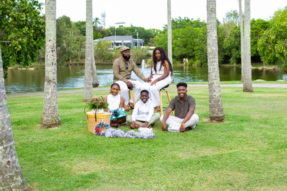 A group relaxes on grass surrounded by tall palm trees during an outdoor gathering.