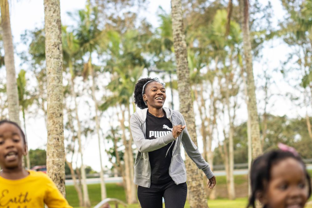 People sharing joyful moments while playing outdoors among trees in a park.