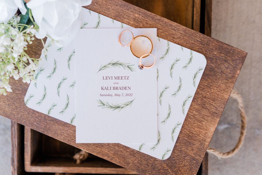 Wedding invitations with floral design displayed in wooden box.