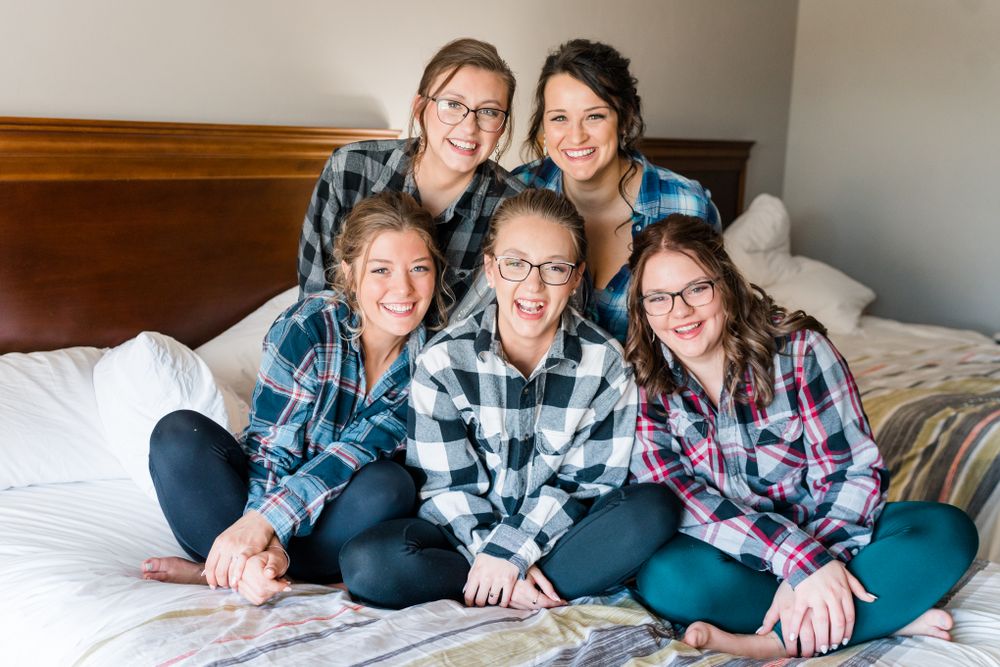 Group wearing plaid shirts sitting together on a bed.