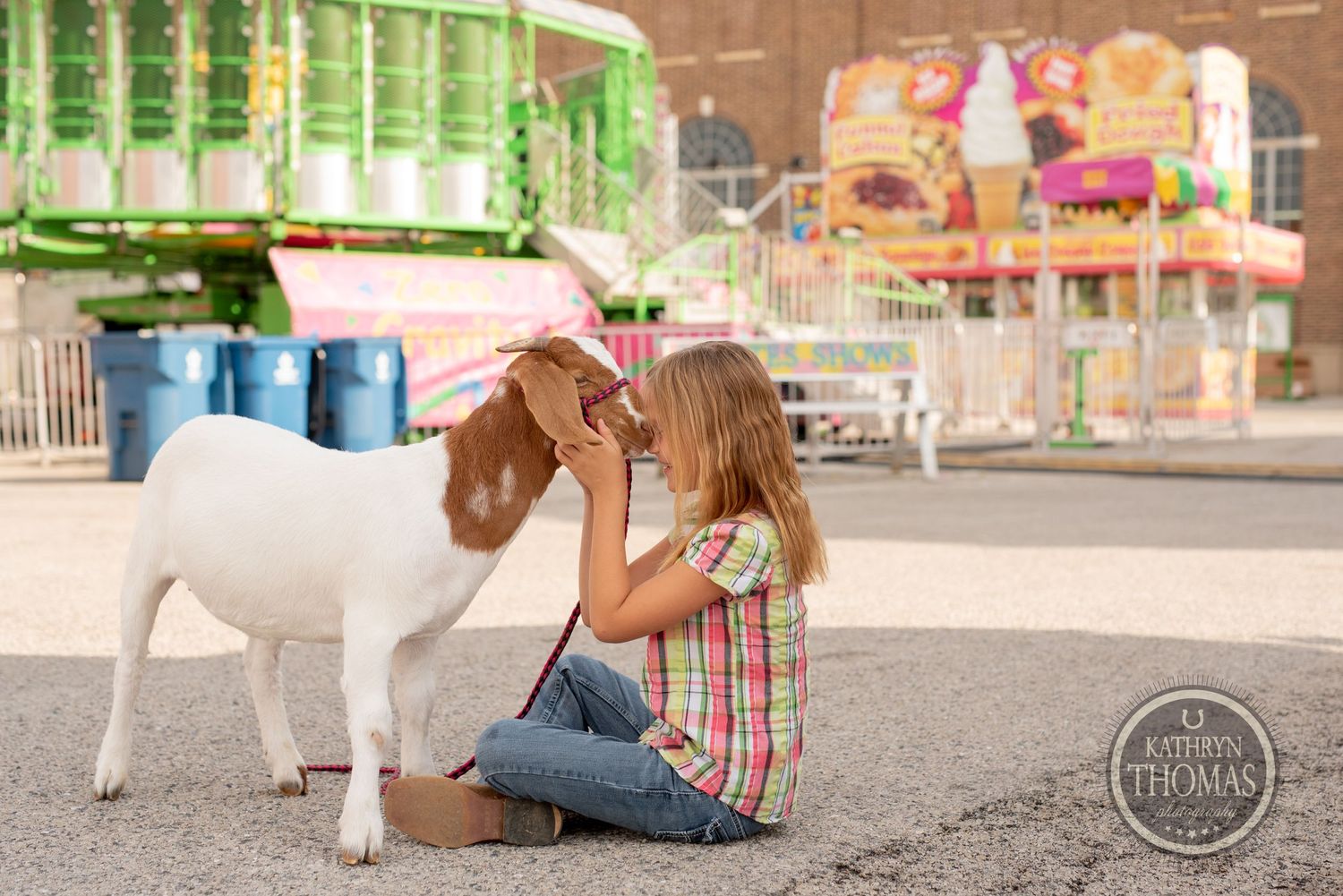 A young exhibitor shows affection to a white goat at the county fair.