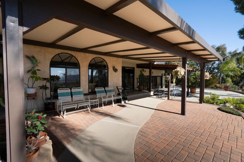 Spacious covered brick patio with seating area and arched windows on a Spanish-style home.