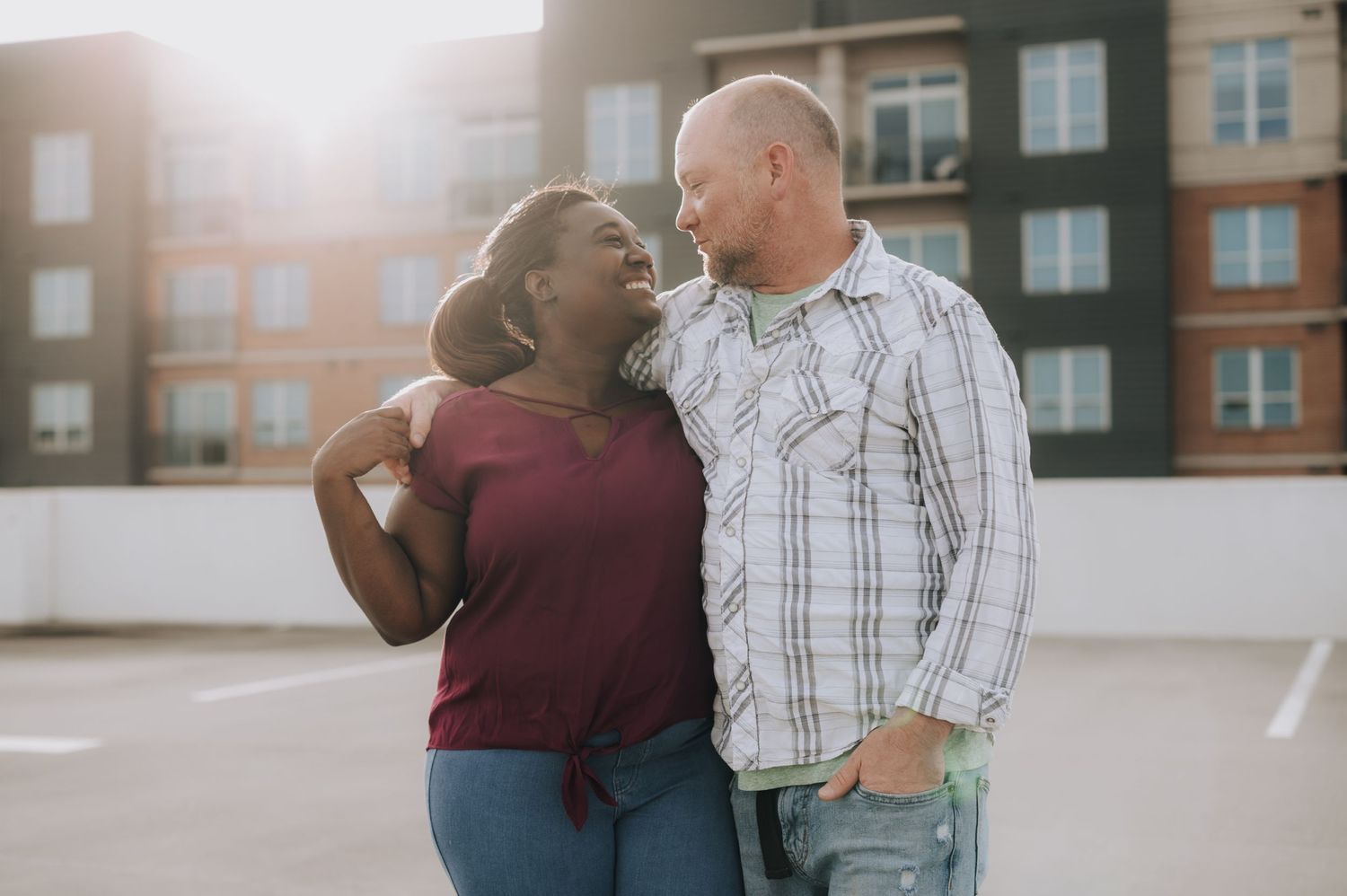 A couple shares a candid laughing moment together in an urban setting.