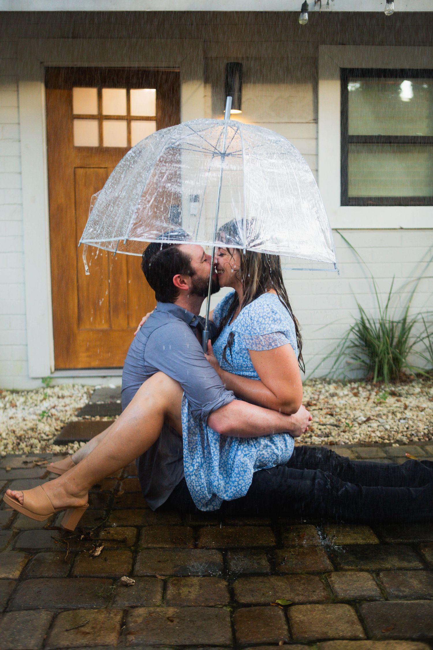 Romantic couple sharing moment under clear umbrella in the rain.