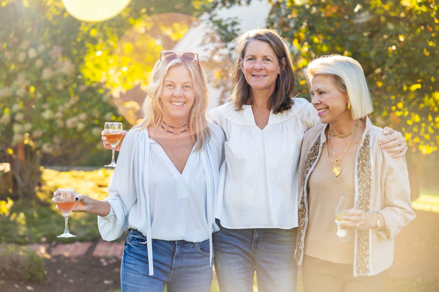 Three friends sharing laughs at sunset outdoor gathering.