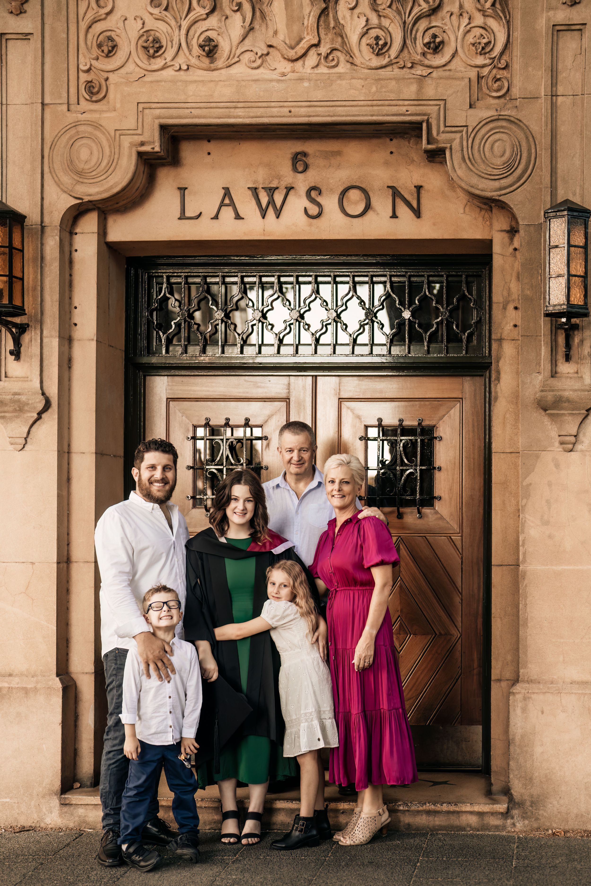 Multi-generational family poses for portrait in front of historic Lawson building entrance.