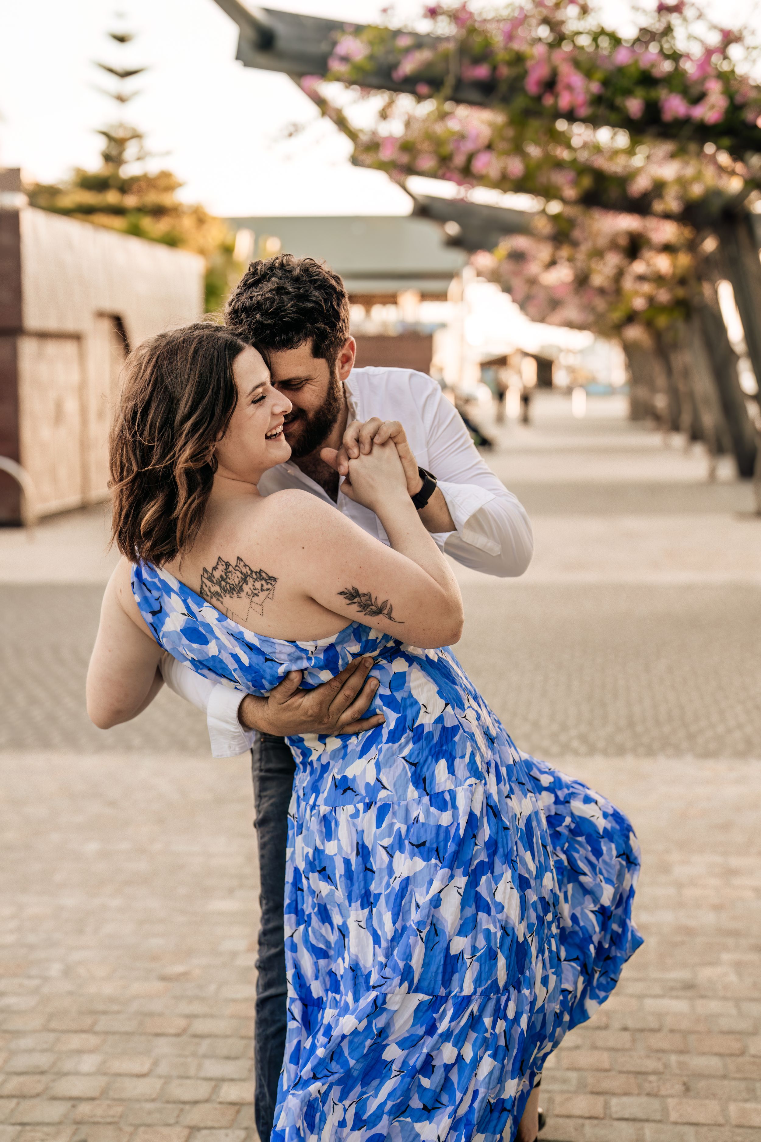 Dancing couple shares intimate moments on cobblestone pavement during sunset.