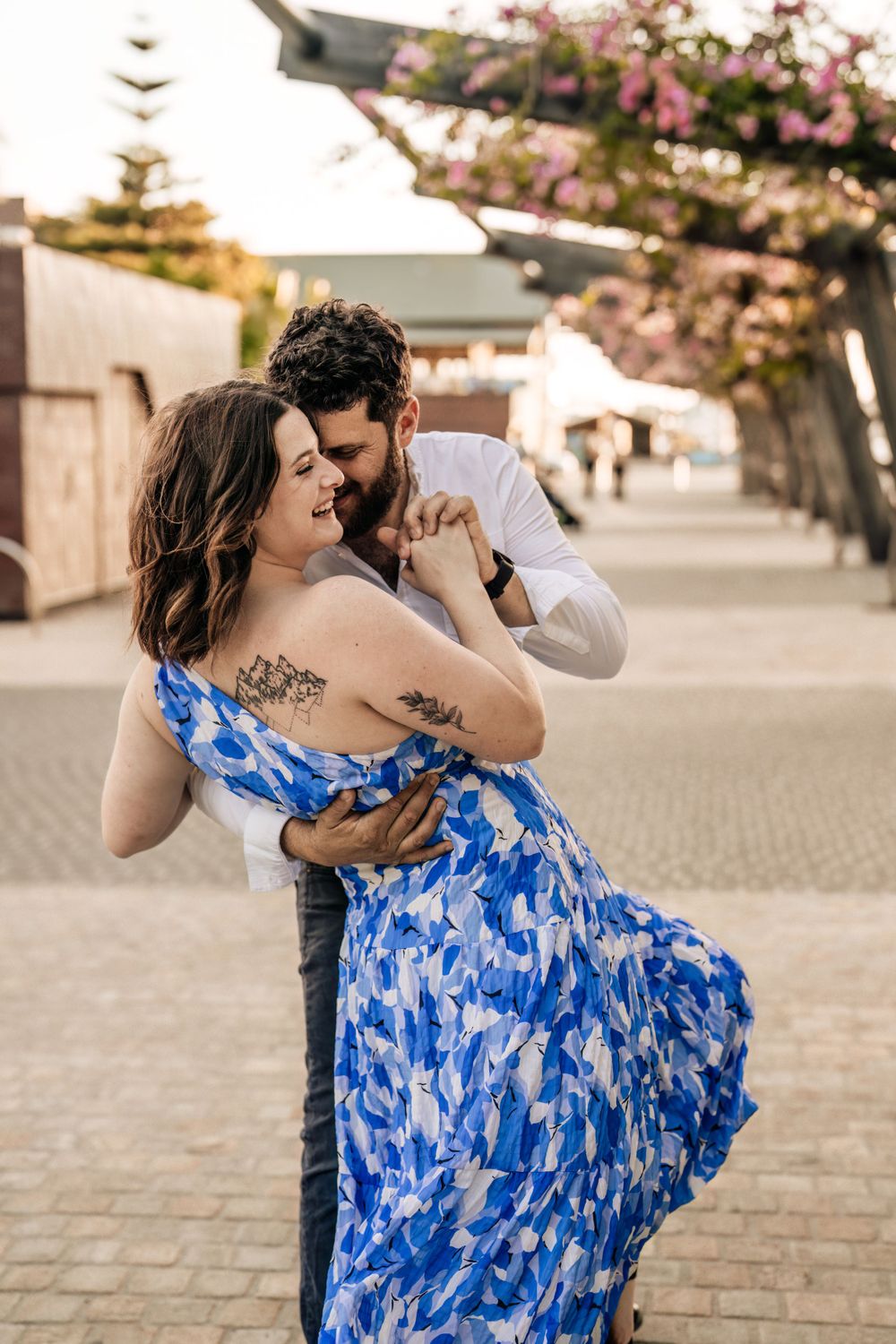 Dancing couple shares intimate moments on cobblestone pavement during sunset.