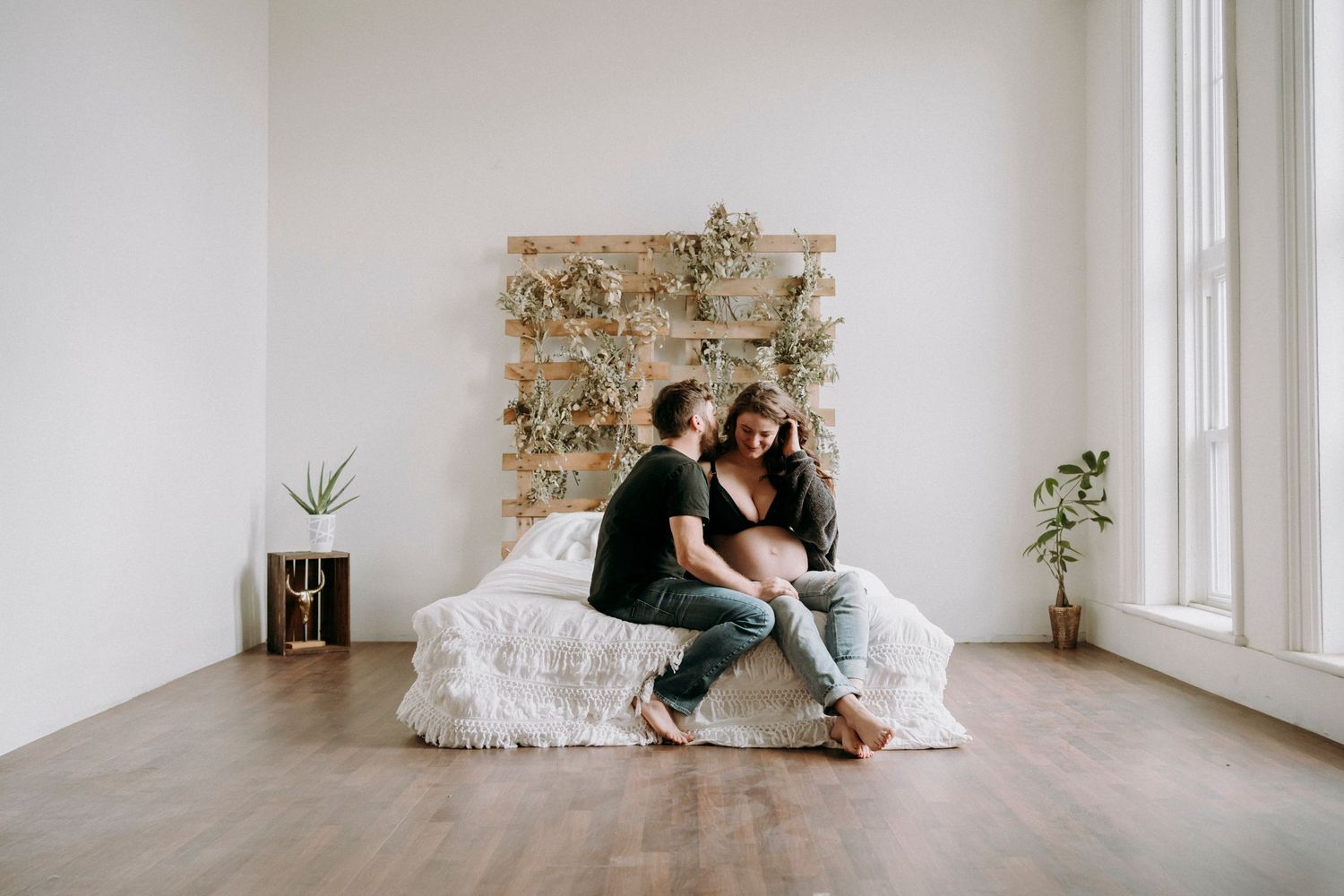Couple sitting together in minimalist white room with floral wall decoration.