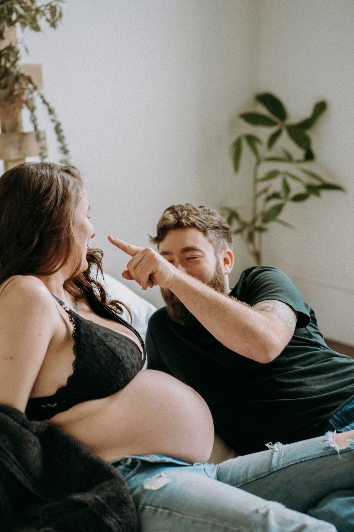 Playful interaction between expectant couple during indoor maternity photo session.