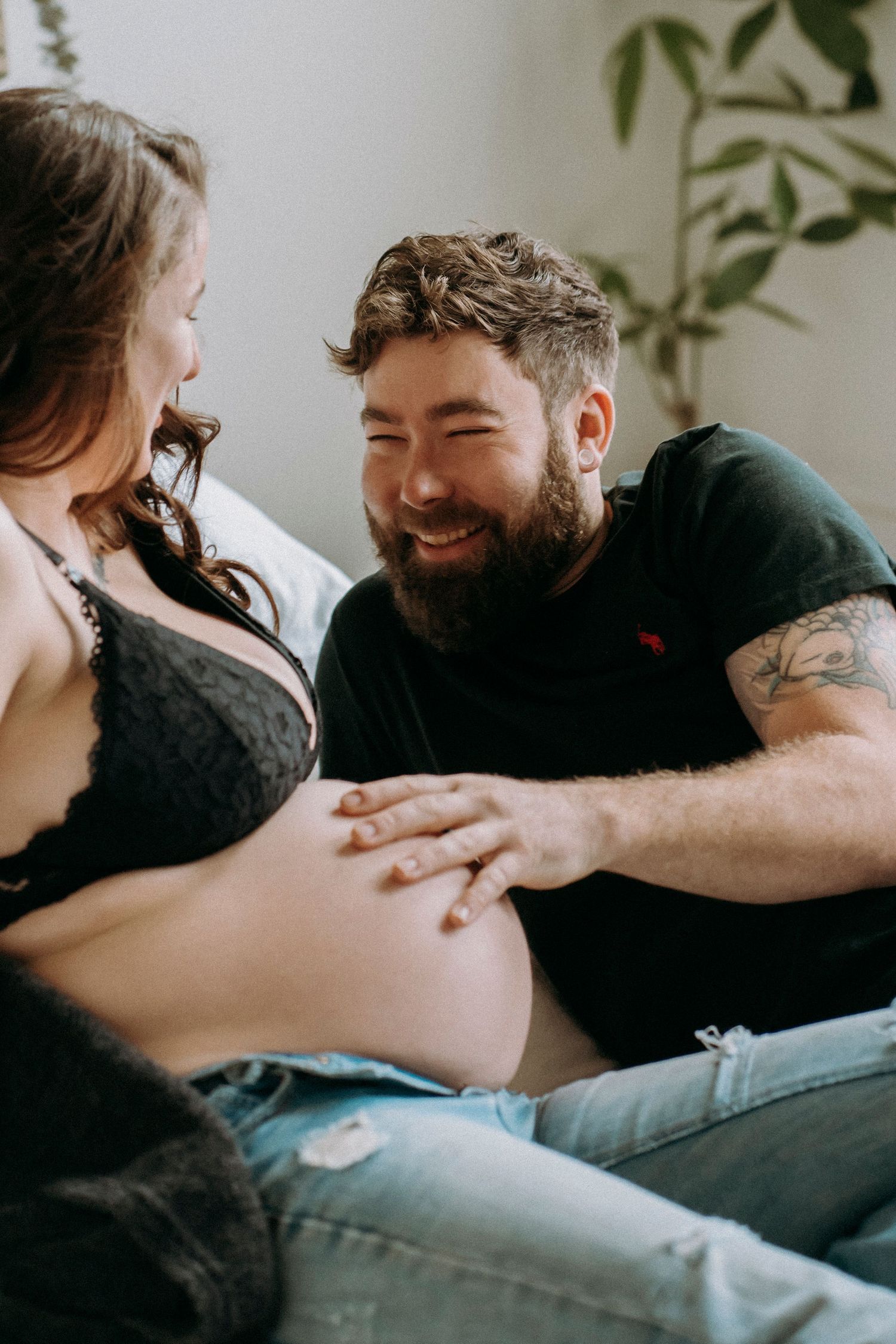 Couple sharing tender moment during pregnancy photoshoot in bright indoor setting.