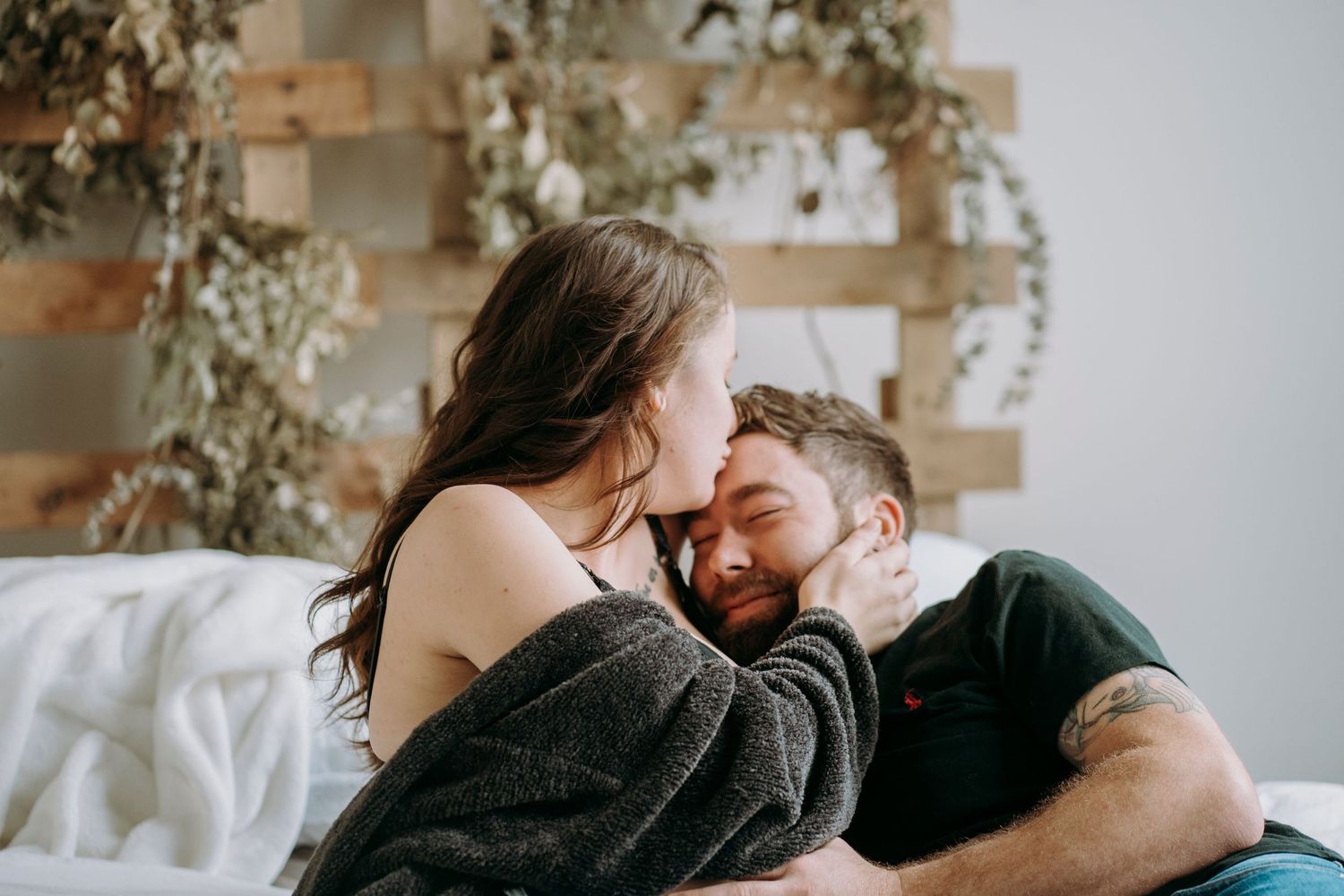 Intimate moment captured during maternity photoshoot with decorative wall backdrop.