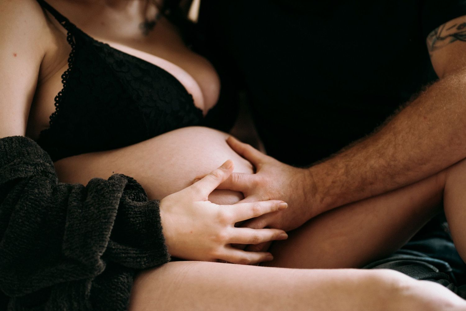 Close up of hands resting on leg in intimate boudoir setting.