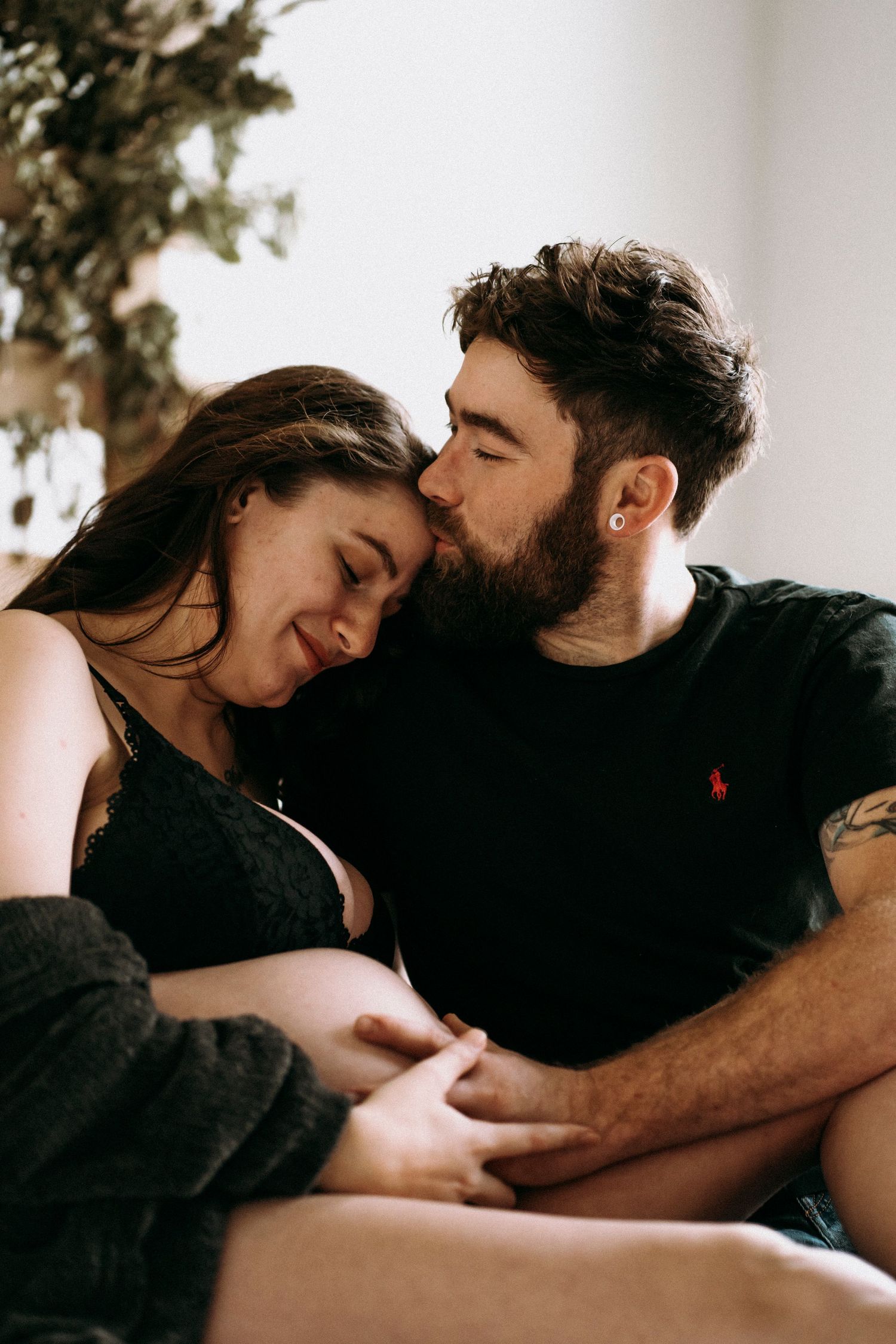 Intimate couple sharing tender moment on bed with rustic wooden panel backdrop.