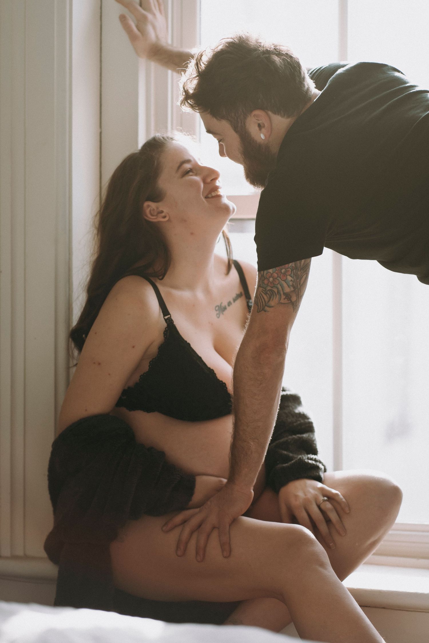 Intimate moment captured by window with natural sunlight streaming in.