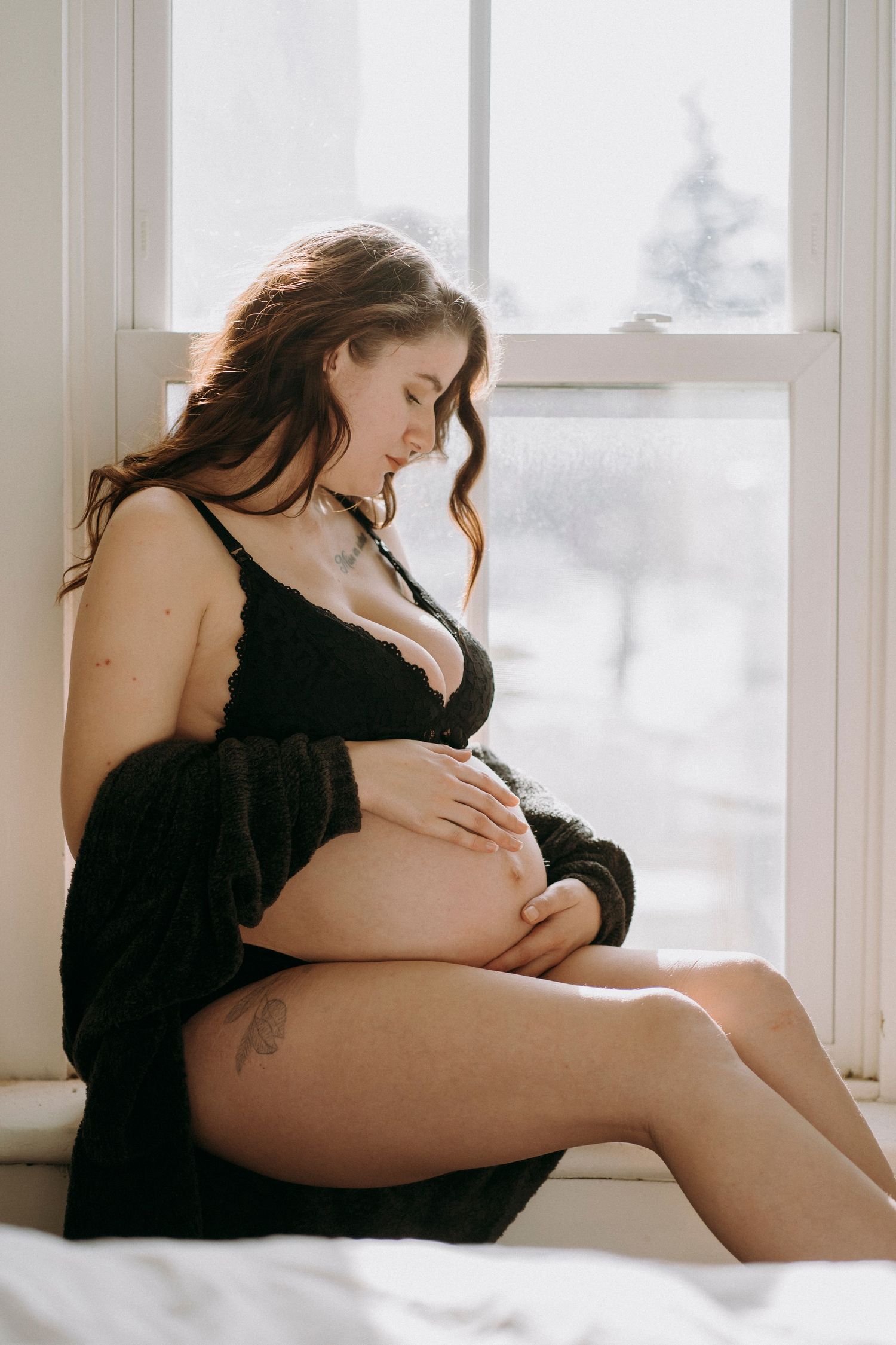 Dreamy boudoir portrait by window with soft natural lighting.