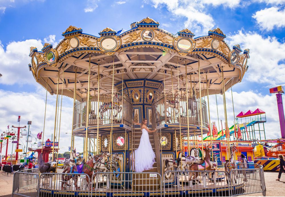 A classic carousel with ornate details stands against a bright blue sky at a carnival.