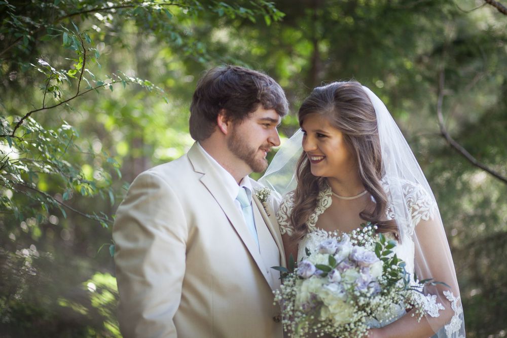 A tender wedding moment captured in soft focus with greenery in the background.