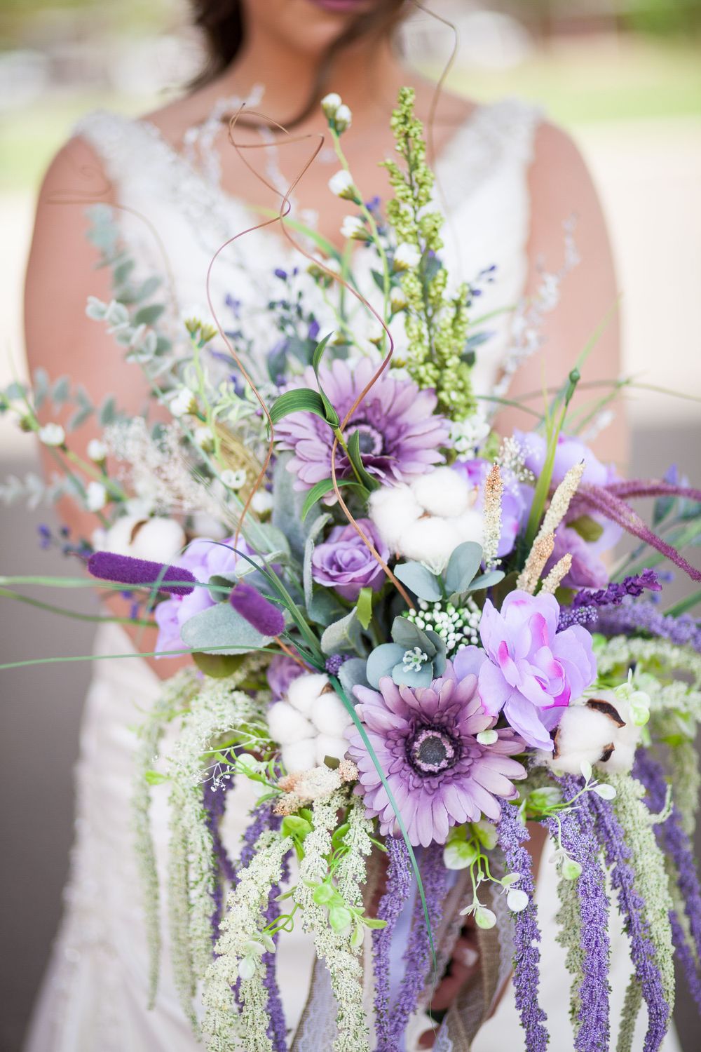 Stunning purple and white wedding bouquet with anemones, roses and cascading greenery.