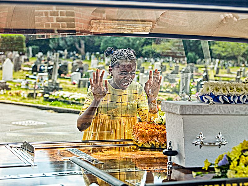 Food service worker behind protective glass serving at cafeteria counter.