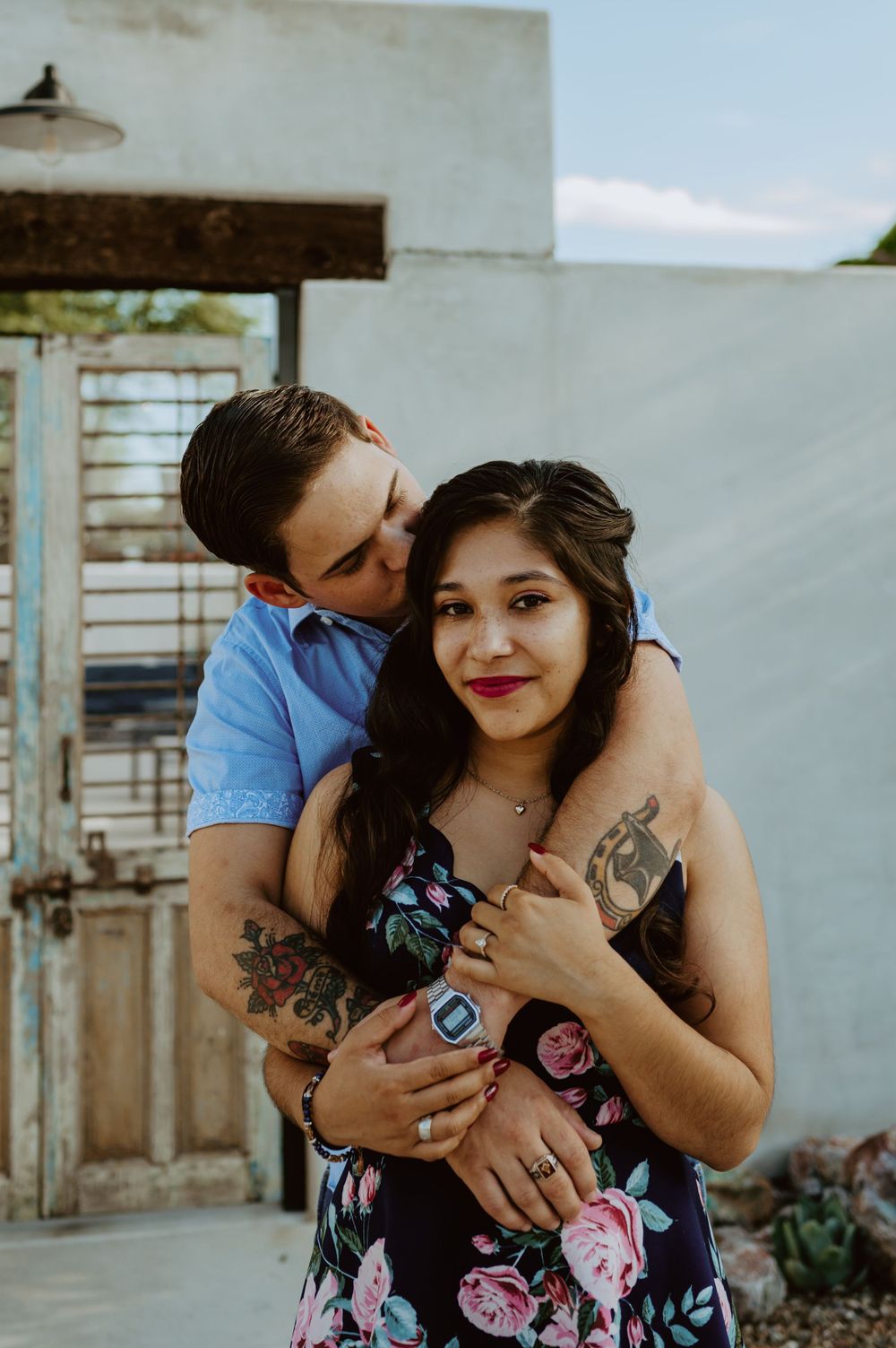 Affectionate moment captured against white building exterior with vintage doors.