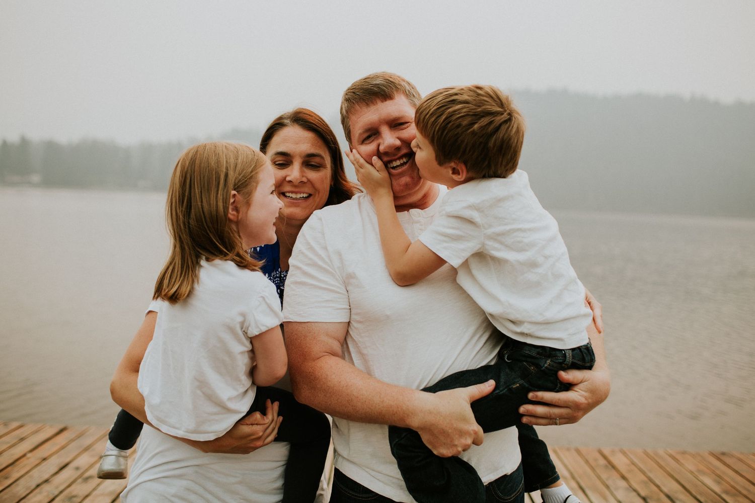 A mom and dad holding their young kids in their arms.