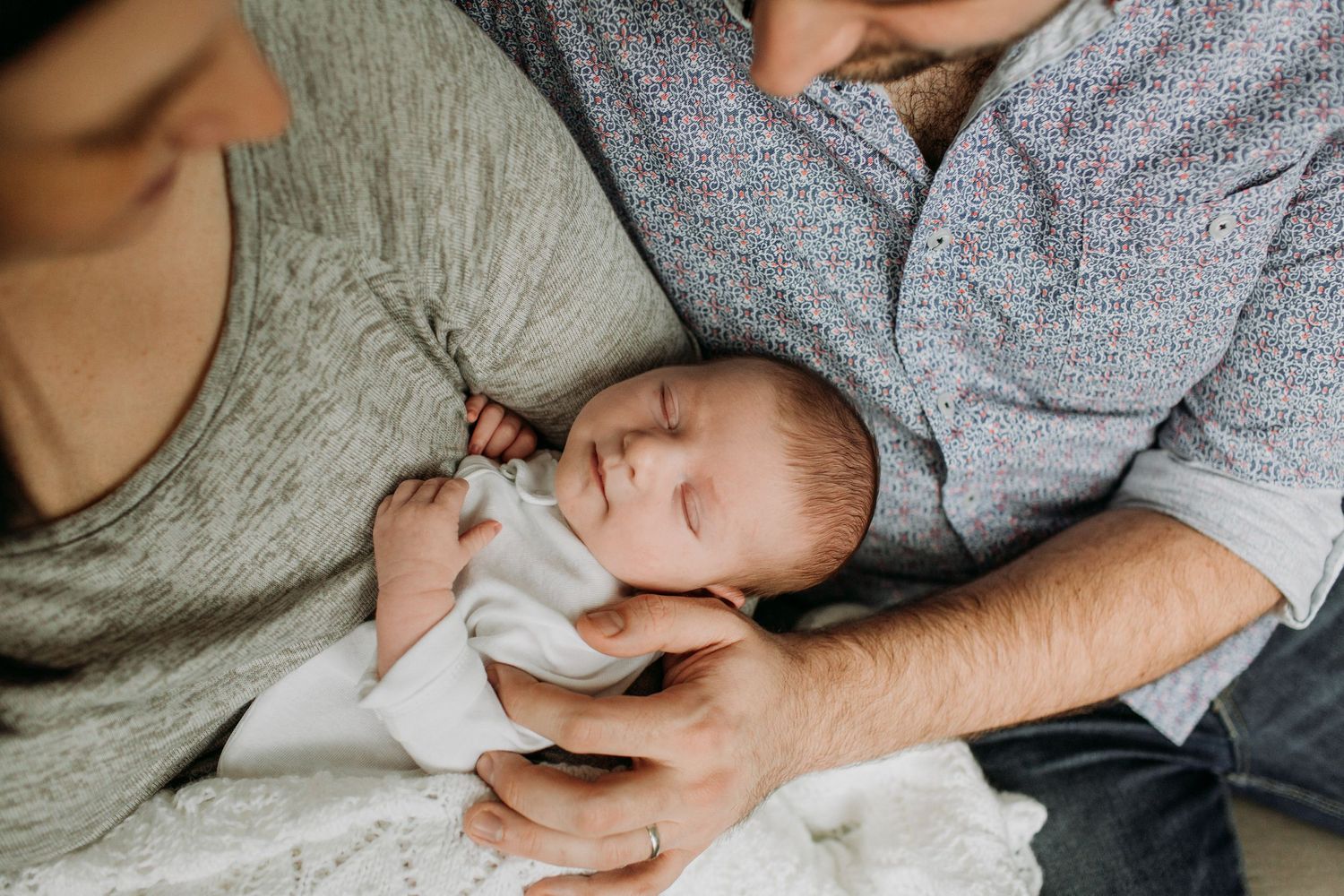 Couple holding a sleeping newborn baby.