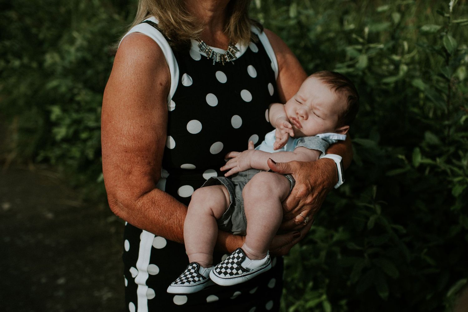 A baby sleeping in a grandmothers arms.